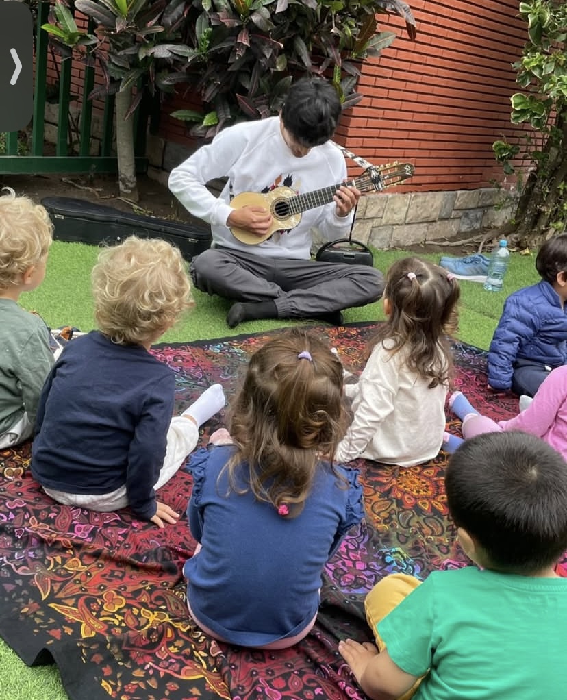 Docente con instrumento de cuerda y niños al rededor